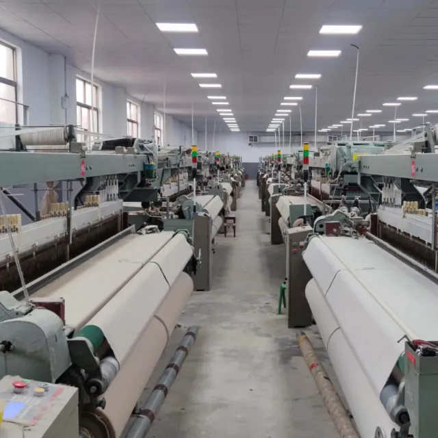 Rows of air-jet looms weaving polyester greige fabric in a partner mill